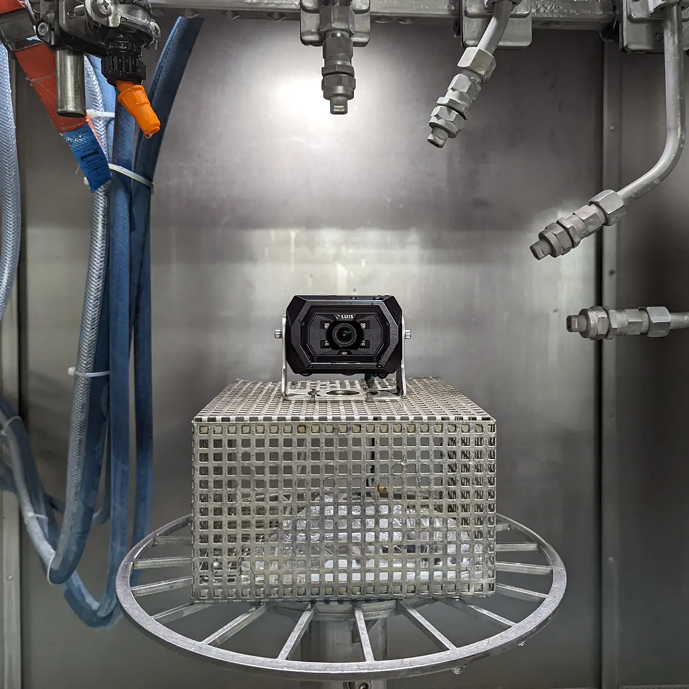 An industrial vision system camera undergoing testing inside a washing chamber.